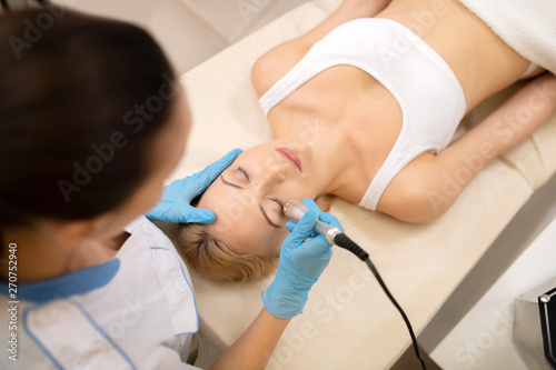 Young woman having laser skin treatment in beauty salon
