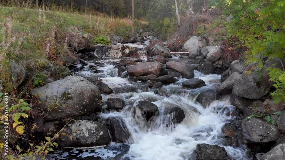 A small stream with rocks and some debris. Cascading down several levels. Vegetation either side A small stream with rocks and some debris. Cascading down several levels. Vegetation either side