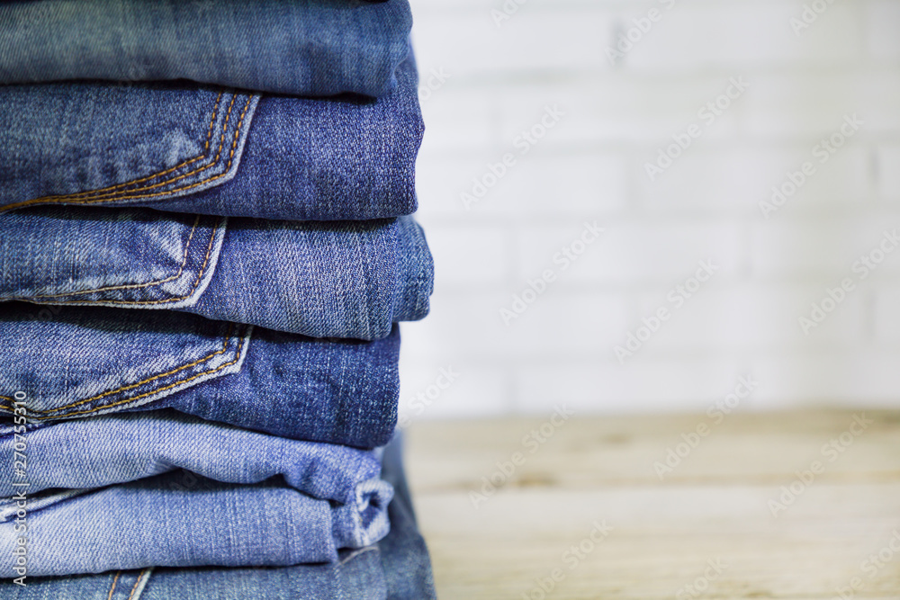 Stack of blue jeans on wooden shelf with copy space. Beauty and fashion clothing concept Stack of blue jeans on wooden shelf with copy space. Beauty and fashion clothing concept