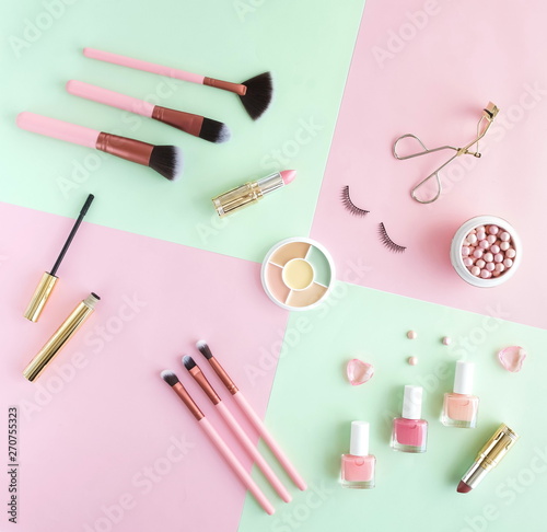 Makeup products, decorative cosmetics on pastel color pink mint background flat lay. Fashion and beauty concept. Top view. Copy space