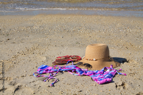 summer accessories on the beach, hat, sunglasses, bikini and footwear, concept of vacation and relaxation