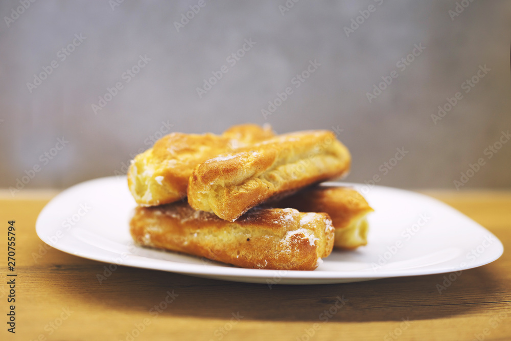 eclairs cakes lie on a white plate. sweet cakes eclairs eclairs cakes lie on a white plate. sweet cakes eclairs