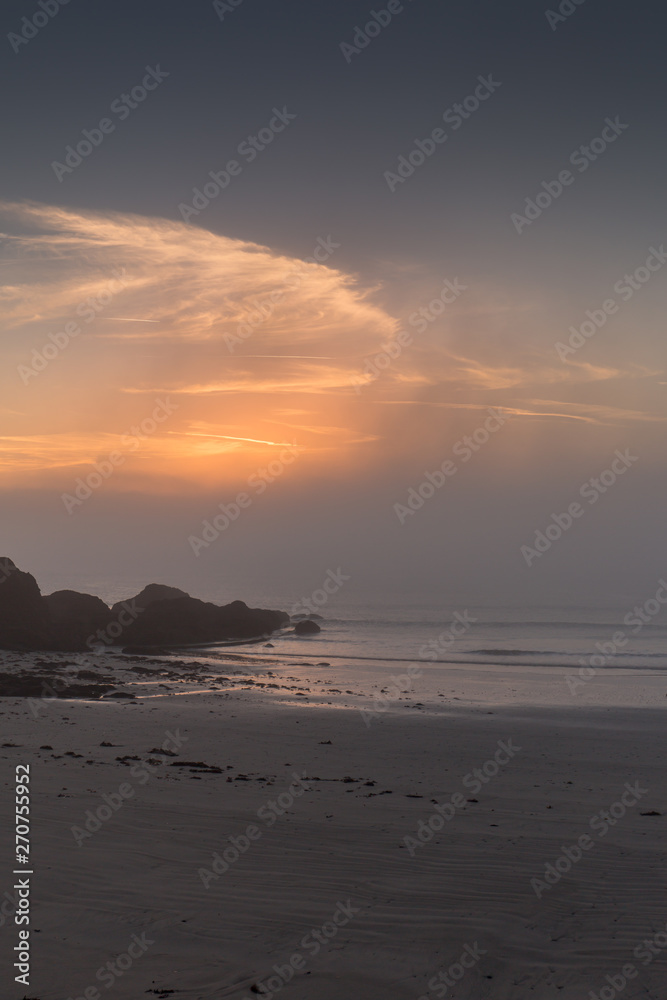 Sunrise at Looe beach with steaming  mist on the sea
