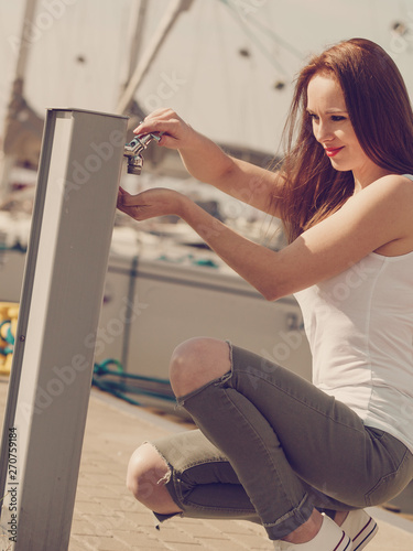 Fashionable woman using water dispenser on pier