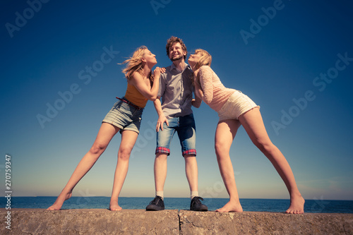 Two girls kissing one boy having fun outdoor