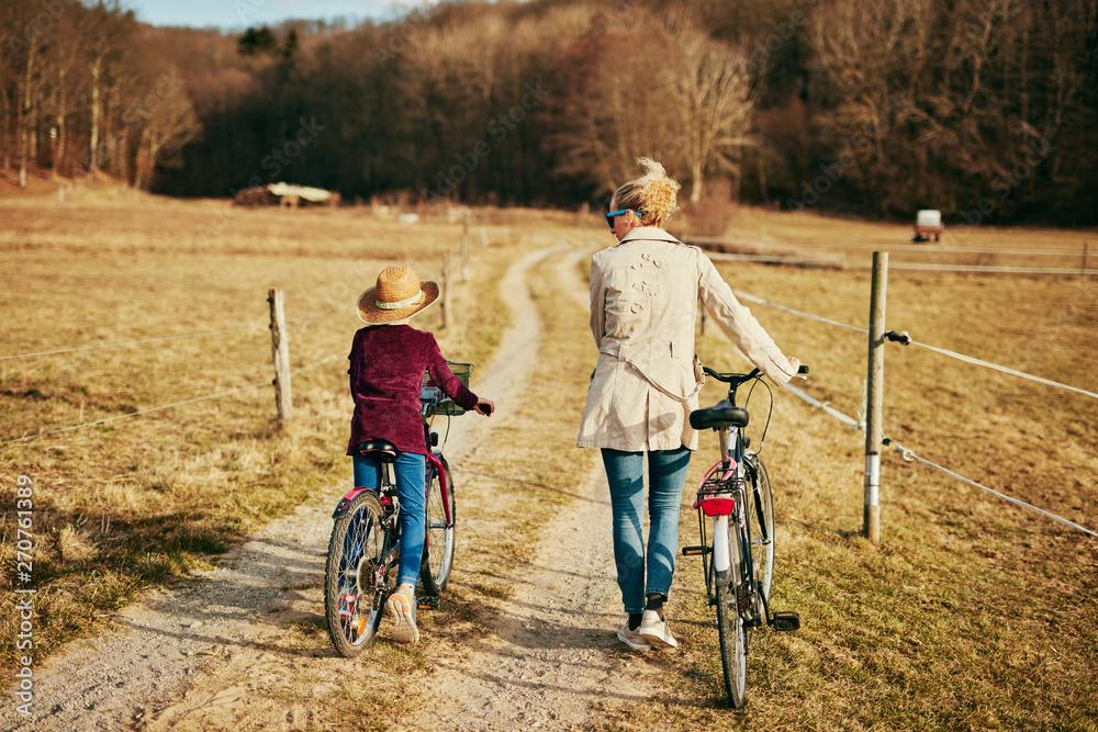 Fototapeta premium Mother and daughter with bicycles on countryside.