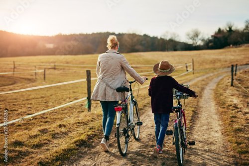 Mother and daughter with bicycles on countryside.