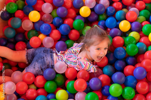 Baby girl is playing in playground with colourful balls