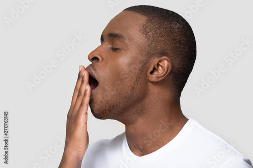 Closeup african male face profile yawning covering mouth with hand photo