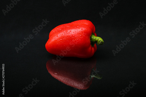 Fotografia red bell pepper with water droplets on black background with reflection