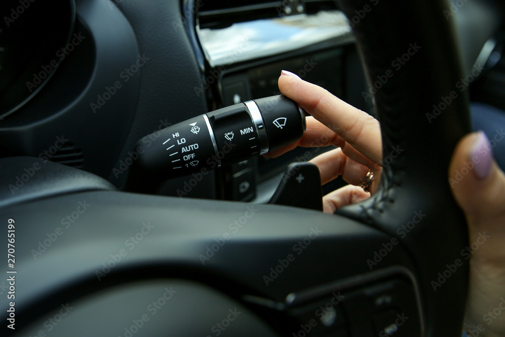 the hand of the driver switches the steering column switch. the hand of the woman turn on the wipers on the car close up the hand of the driver switches the steering column switch. the hand of the woman turn on the wipers on the car close up