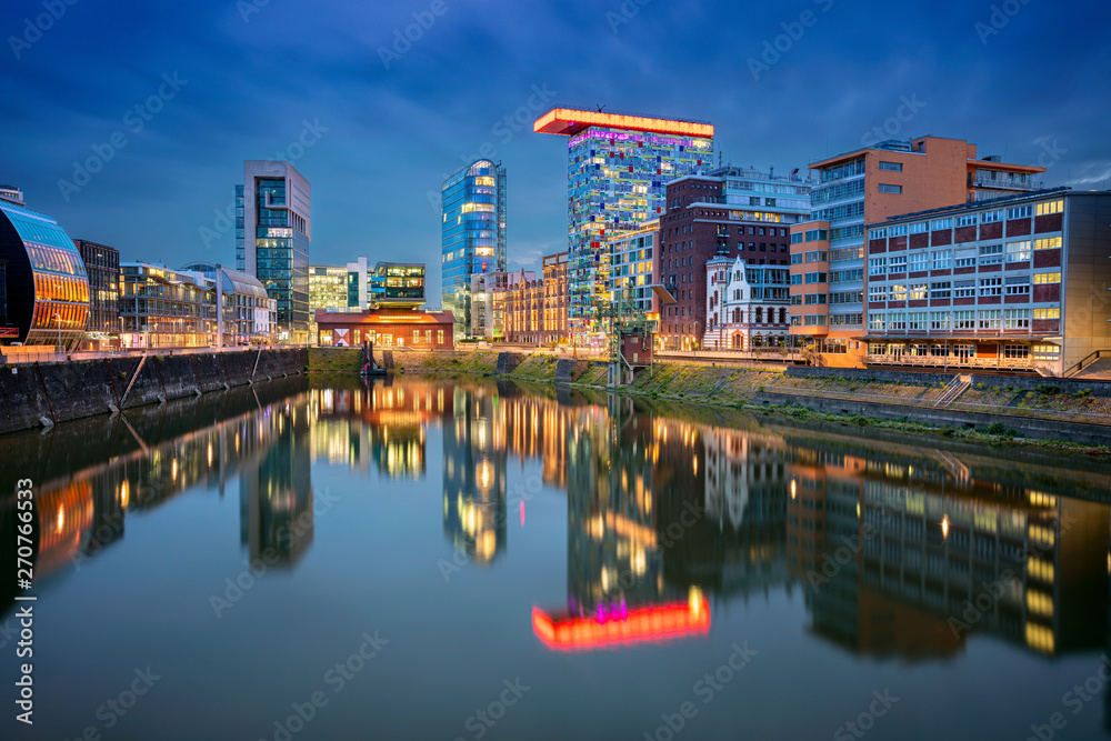 Dusseldorf, Germany. Cityscape image of Düsseldorf, Germany with the Media Harbour and reflection of the city in the Rhine river, during twilight blue hour.