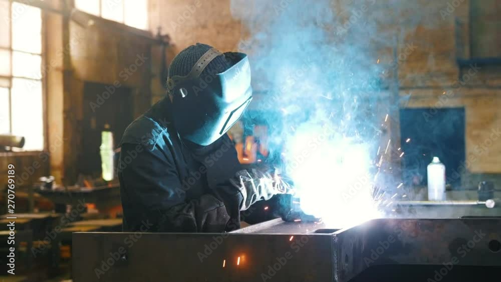 Construction plant. A man worker in a helmet using a welding machine Construction plant. A man worker in a helmet using a welding machine