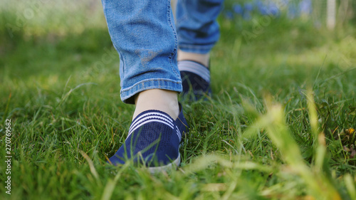 Young woman in blue sneakers goes on a meadow
