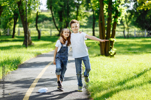 Fototapeta Naklejka Na Ścianę i Meble -  Picture of brother and sister having fun in the summer park on sunset. Cheerful children hugs and laughing. Little girl and boy playing outdoors, best friends, happy family, love and happiness concept