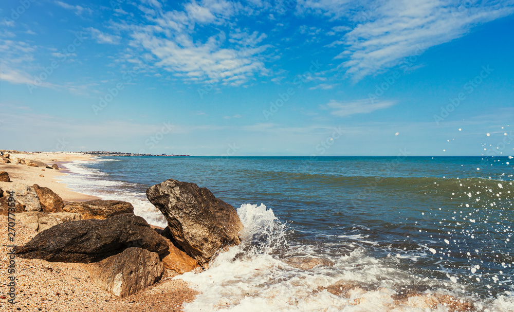 Summer beach with rocks and splashing waves