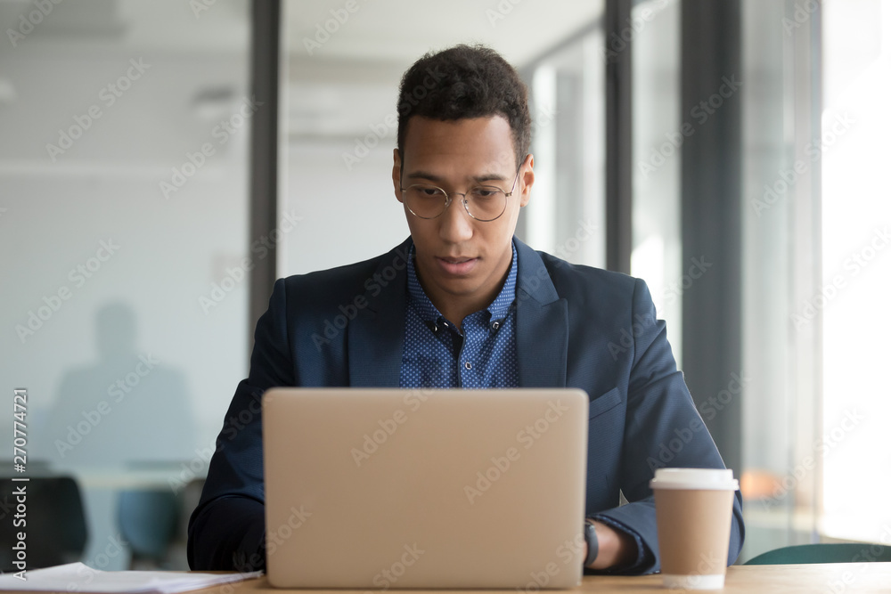 Concentrated african American businessman working at laptop in office
