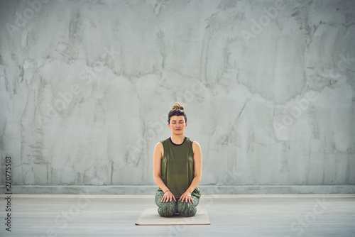 Front view of beautiful Caucasian brunette in sprtswear sitting in Thunderbolt yoga pose.