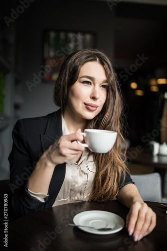 Smiling woman in a good mood with cup of coffee sitting in cafe.