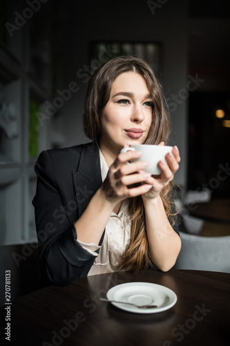 Smiling woman in a good mood with cup of coffee sitting in cafe.