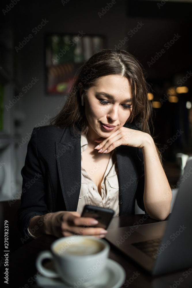 Woman typing write message on smart phone in a modern cafe. Young pretty girl sitting at a table with coffee or cappuccino using mobile phone. Woman typing write message on smart phone in a modern cafe. Young pretty girl sitting at a table with coffee or cappuccino using mobile phone.