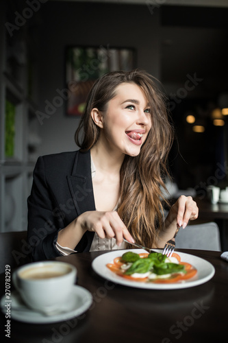 Young pretty woman is eating mixed vegetable salad in cafe
