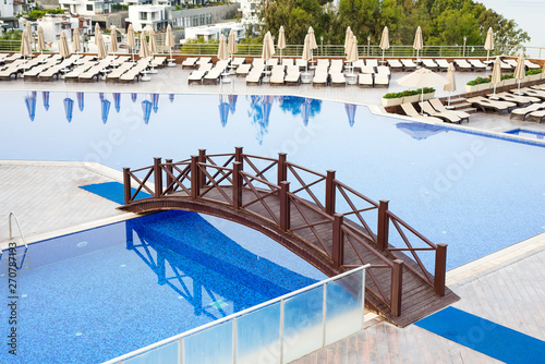 Outdoor luxury swimming pool, umbrellas, sun beds with reflection in the water at the holiday, relax place.