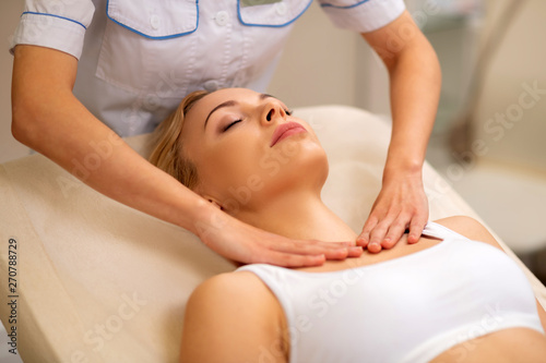 Blonde-haired woman closing eyes while having neck massage