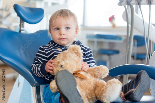 Little toddler boy with teddy bear toy at dentist's clinic for routine check-up