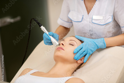 Dermatologist touching face of client while doing skin tightening photo