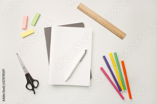 the white notebook lies on a gray notebook in the form of a blank on a white background with a white pen markers colored stickers with black scissors and a brown ruler