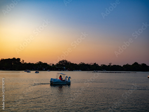 women riding duck pedal boat is lined up in the sunset. water bicycles locked on the lake in a sunny autumn day . active recreation objects