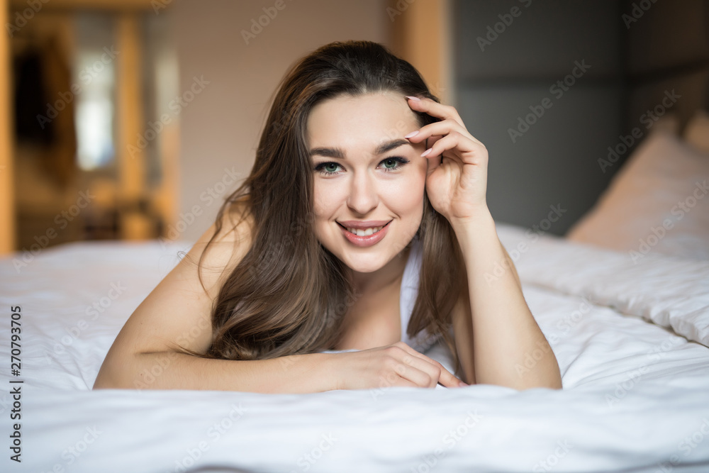 Beautiful day dreamer. Beautiful young woman holding hands behind head while lying in bed and smiling Beautiful day dreamer. Beautiful young woman holding hands behind head while lying in bed and smiling