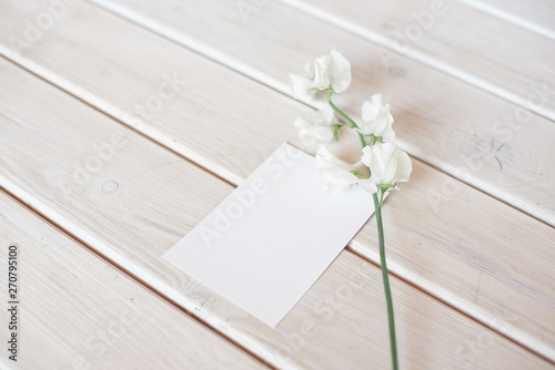 Wedding invitation birthday gift certificate for a spa or care decorated letter card on a white wooden table with a branch of white flowers.