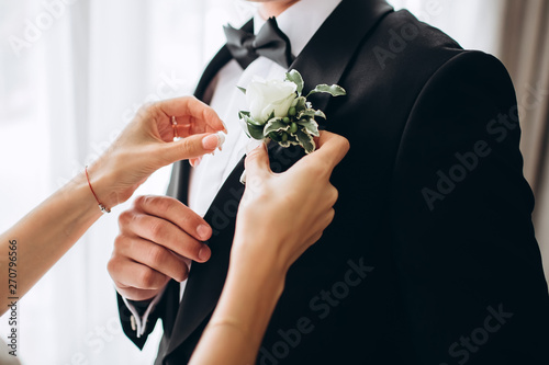 stylish groomsmen helping happy groom getting ready in the morning for wedding ceremony. luxury man in suit in room. wedding day.