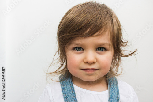 Beautiful blonde Caucasian toddler child with blue eyes closeup portrait. Calm and serious attentive girl on isolated background