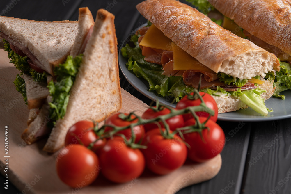 Baguette and sandwich on black table. Fresh bread. Food. Lunch. Meal with tomato. Healthy dinner. Kitchen Baguette and sandwich on black table. Fresh bread. Food. Lunch. Meal with tomato. Healthy dinner. Kitchen
