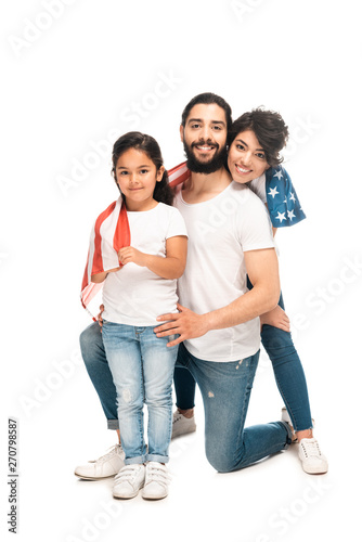 cheerful latin family smiling while holding american flag isolated on white