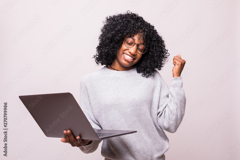 Portrait of a happy emotional african woman using laptop computer make winner gesture posing isolated over white background Portrait of a happy emotional african woman using laptop computer make winner gesture posing isolated over white background
