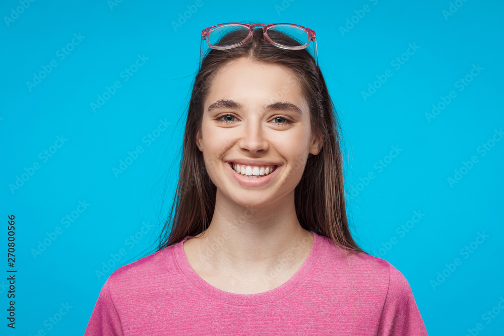 Close-up studio portrait of young smiling attractive female isolated on blue background Close-up studio portrait of young smiling attractive female isolated on blue background