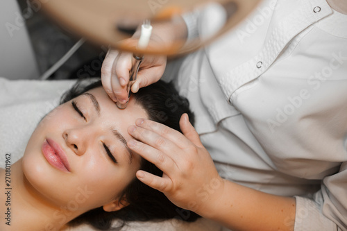 Upper view of a lovely caucasian woman doing microdermabrasion procedure on her face in spa wellness center. photo