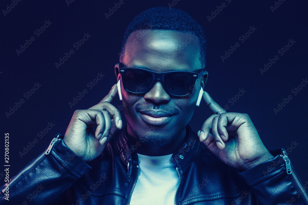 Portrait of handsome young african man listening music with wireless earphones