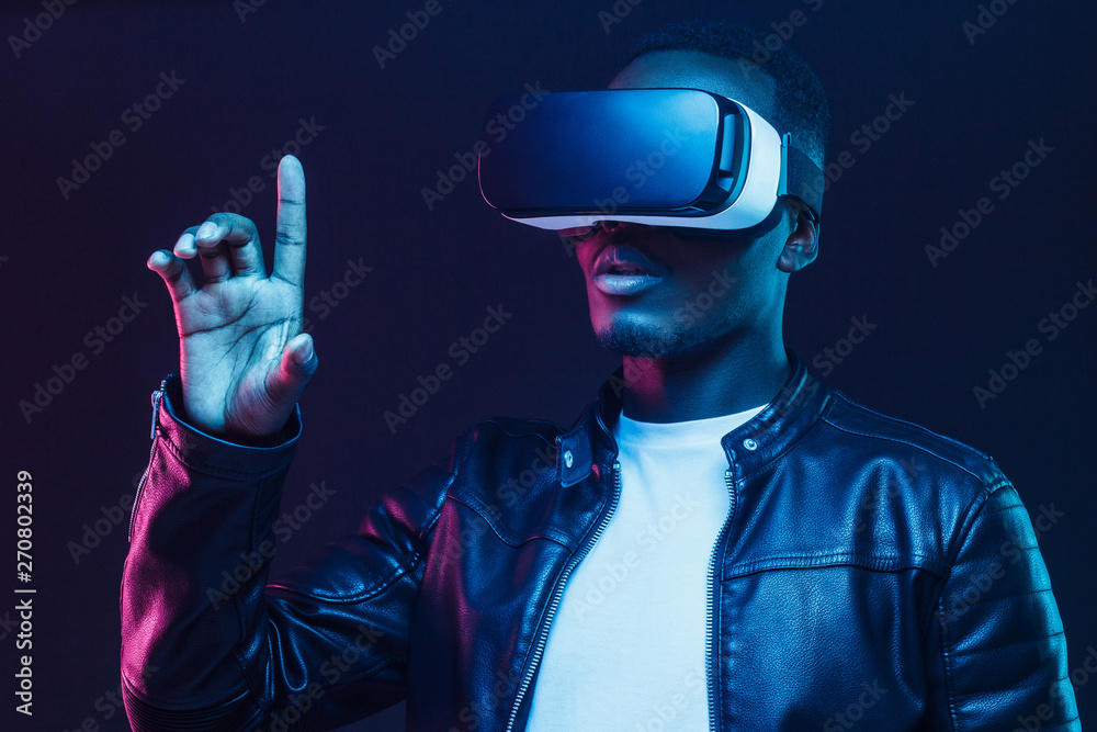 African american man in vr glasses, using virtual reality headset, trying to touch something with finger African american man in vr glasses, using virtual reality headset, trying to touch something with finger