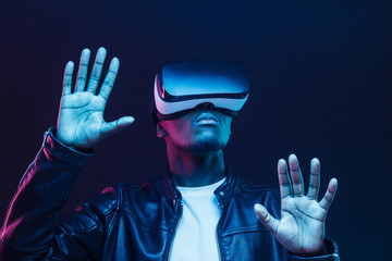 African man in vr glasses, playing video games with virtual reality headset, trying to touch something with hands
