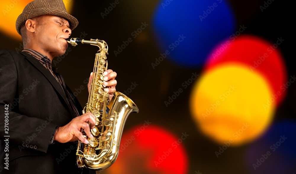 Obraz premium Close-up man playing on saxophone on blurred background