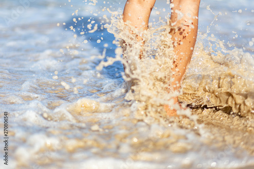 Sea foam, waves and naked feet on a sand beach. Holidays, relax, summer background 