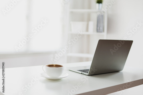 white and clear office room with laptop and coffee on table