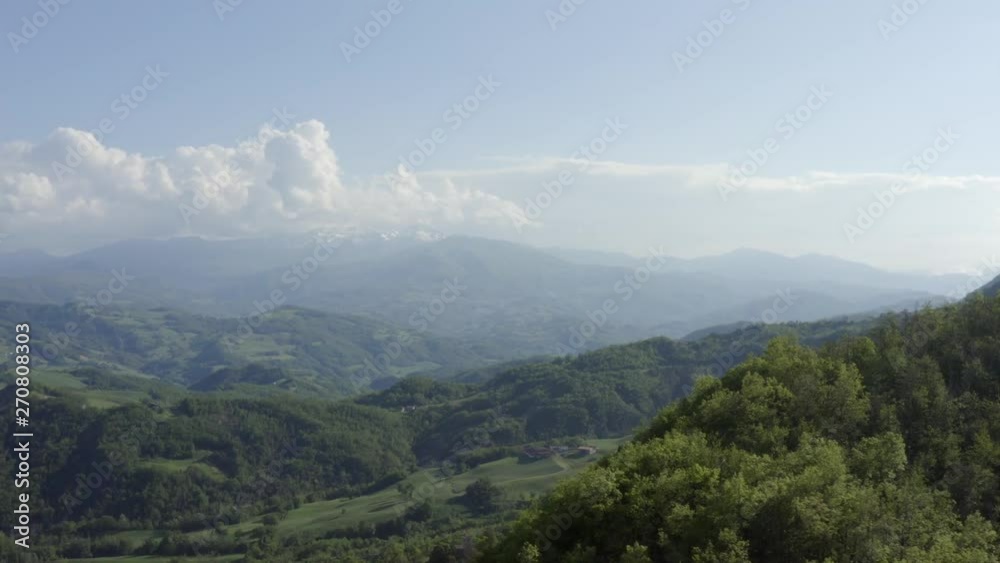 Wide angle view of drone flying over wooded hill top and turning to show the surrounding rural countryside near Castle Carpinete in Reggio Emilia in Italy. Wide angle view of drone flying over wooded hill top and turning to show the surrounding rural countryside near Castle Carpinete in Reggio Emilia in Italy.