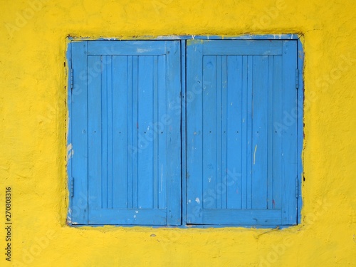 old blue wood window close on yellow wall