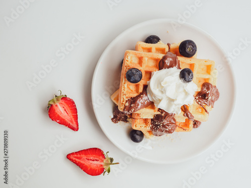 Summer breakfast flat lay. Top view tasty waffle with fruits, chocolate and whipped cream